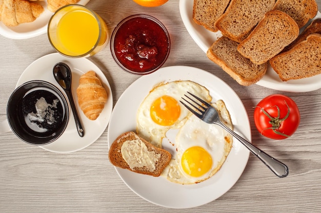 Plate with fried eggs and fork at the table with cup of black coffee