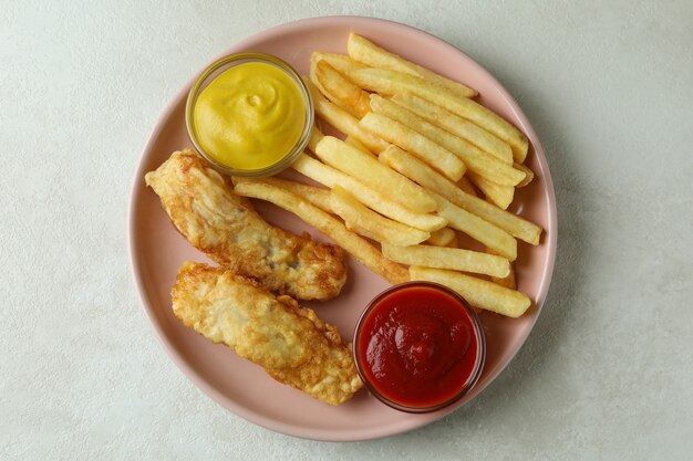 Plate with fried fish and chips on gray textured table