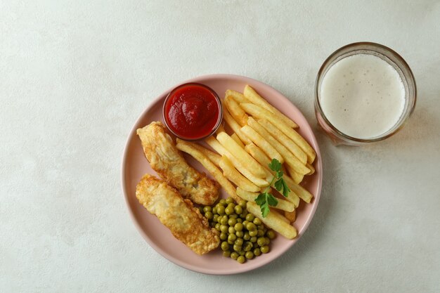 Plate with fried fish and chips on white textured table