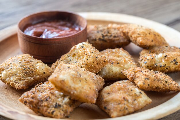 Piastra con ravioli fritti sulla tavola di legno