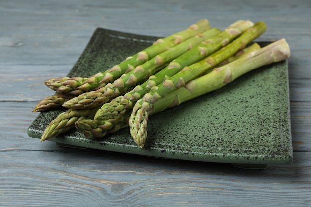 Plate with green asparagus on wooden