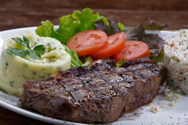 Plate with grilled steak rice potatoes salad Picanha