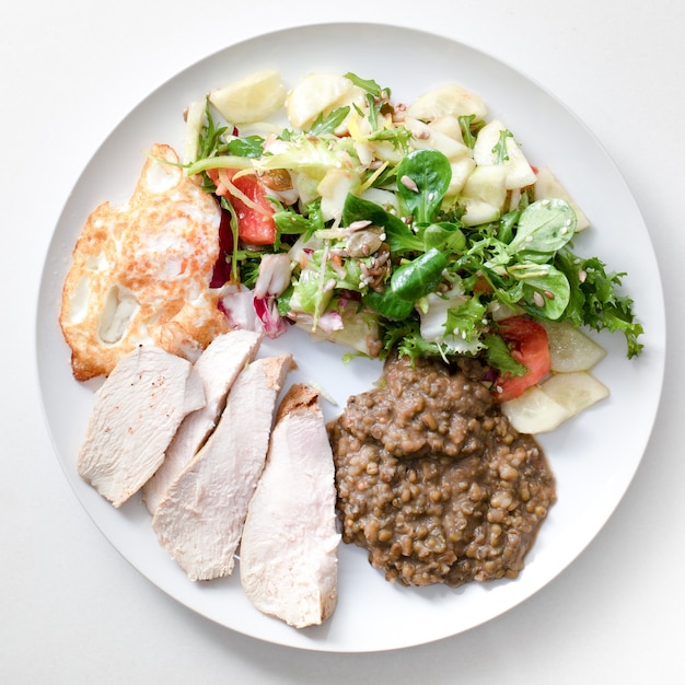 A plate with a healthy breakfast. Beans, roasted chicken wing.