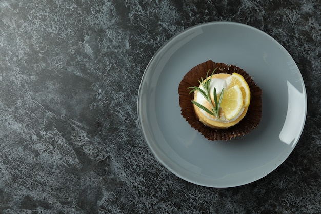 Plate with lemon cupcake on black smokey table