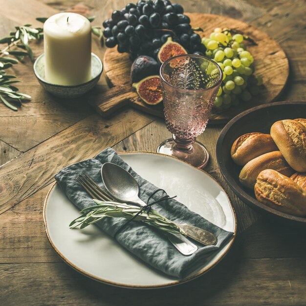 Plate with linen napkin fork spoon glass candle fruits bread