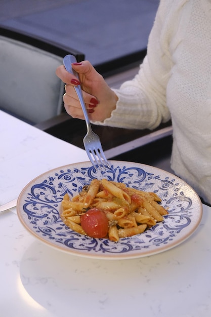 Photo a plate with macaroni and cheese on it is being eaten by a woman