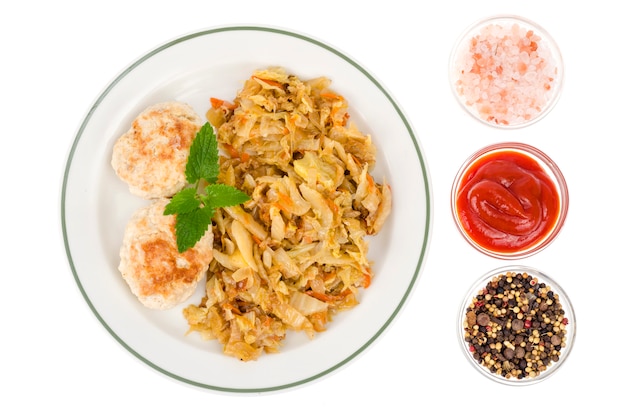 Plate with meat patties and stewed cabbage isolated on white