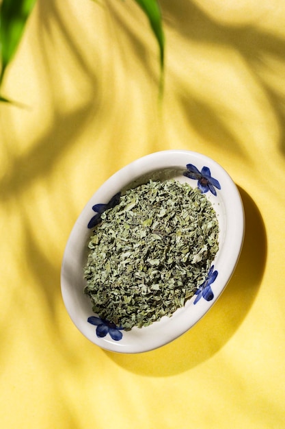 Plate with moringa leaves on a yellow background top view