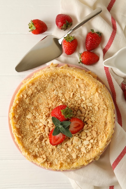 Plate with Napoleon cake with strawberry on white wooden surface