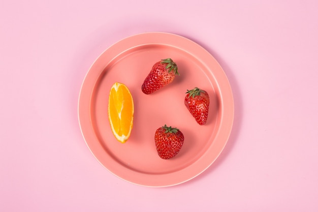 Photo plate with orange slices and strawberries on table