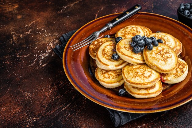 Plate with pancakes with fresh blueberries and syrup . Dark background. Top View. Copy space.