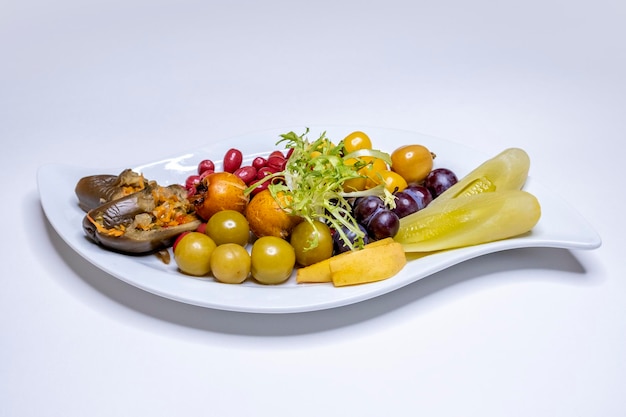 plate with pickles: cucumbers, cabbage, tomatoes, zucchini, cucumbers, onions, cabbage, peppers, carrots, garlic, grapes, eggplant. restaurant menu on a white background. copy space, place for text.