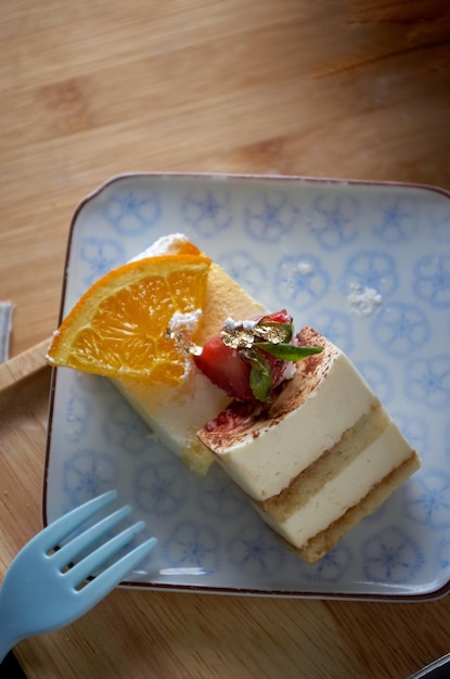 A plate with a piece of cake and an orange slice on it