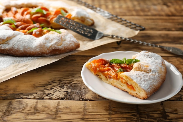 Foto piastra con un pezzo di deliziosa torta di albicocche sul tavolo