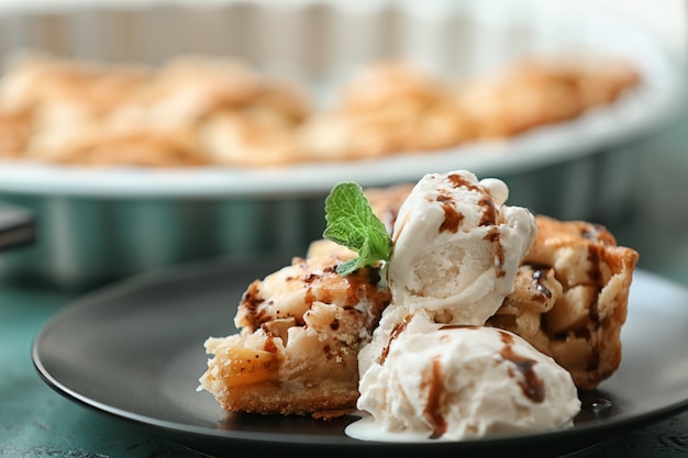 Plate with piece of tasty apple pie and ice-cream on table, closeup