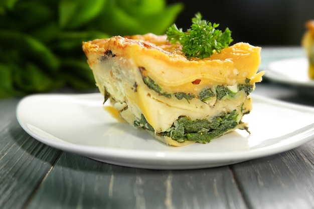 plate with piece of tasty spinach lasagna on wooden table