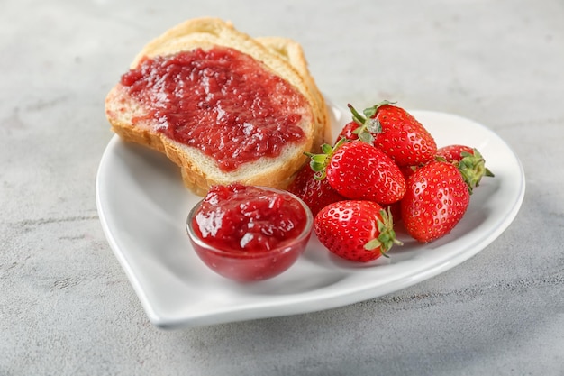 Plate with pieces of bread and strawberry jam on table