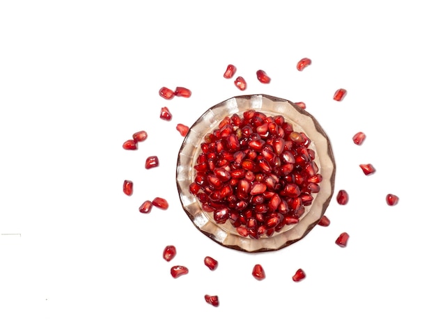 Plate with pomegranate seeds on a white background