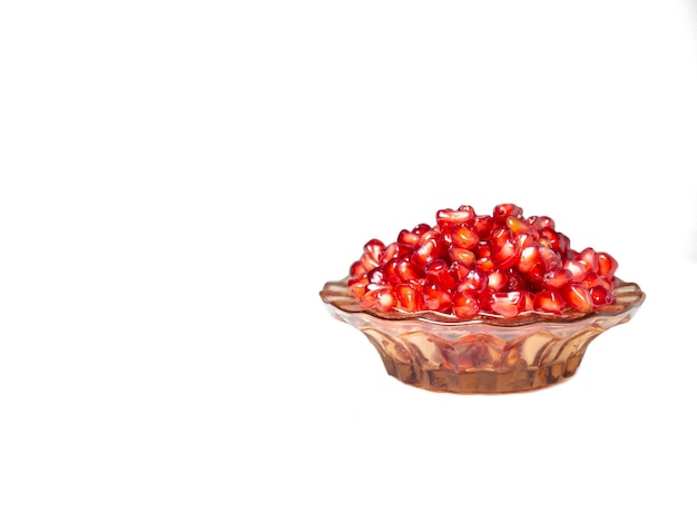 Plate with pomegranate seeds on a white background