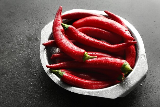 Plate with red chili peppers on gray table