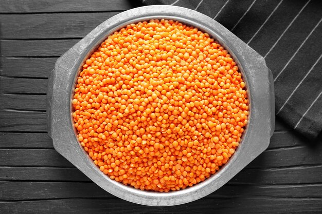 Plate with red lentils on wooden background