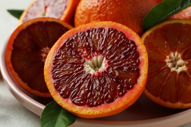 Plate with red oranges and leaves, close up