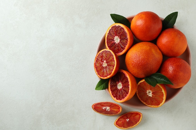 Plate with red oranges and leaves on white textured isolated background