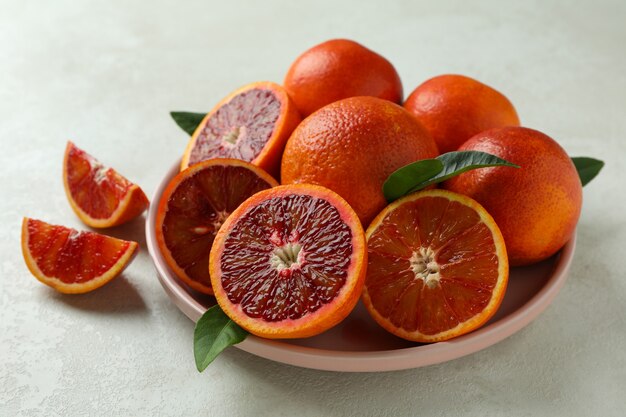 Plate with red oranges and leaves on white textured