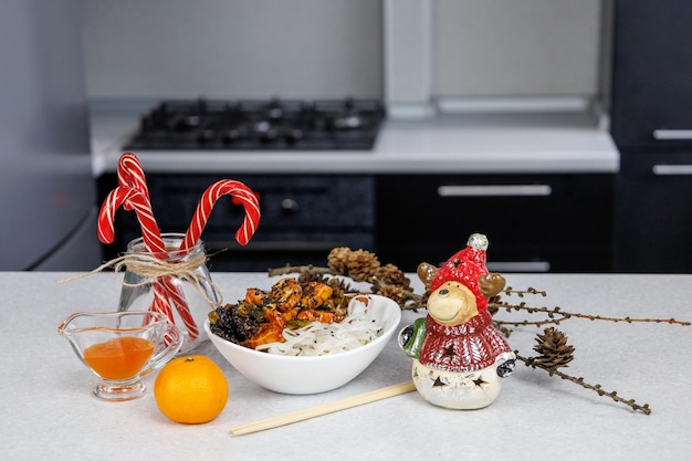 Plate with rice noodles and chicken Food sticks Festive decoration Dark home kitchen background Christmas concept