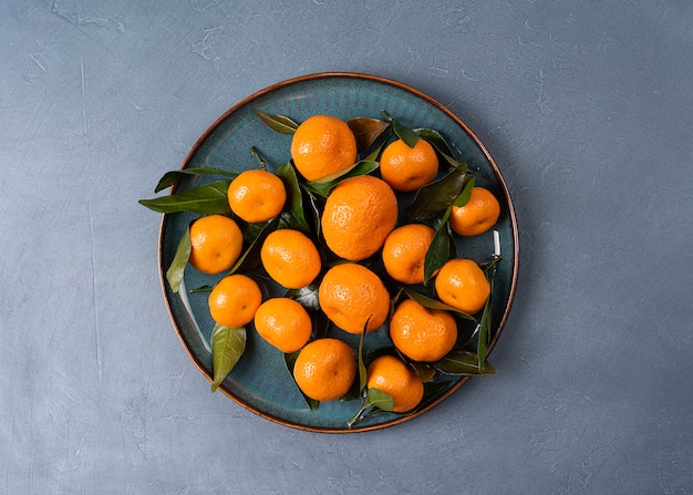 Тарелка со спелыми мандаринами с листьями в высоком разрешении