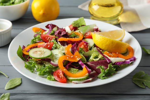 Plate with salad and ingredients on wooden