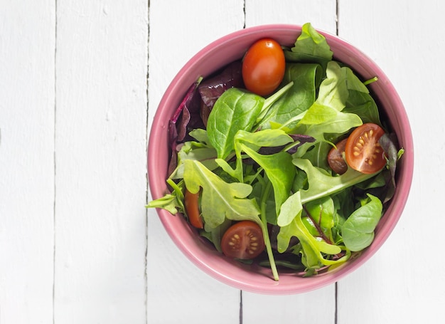 A plate with salad mix on a white wooden background with a copy of the space