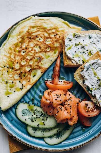 Foto piatto con uova strapazzate, salmone, cetriolo e toast al formaggio cremoso servito per colazione