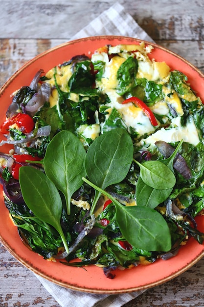 Plate with scrambled eggs with spinach and vegetables.