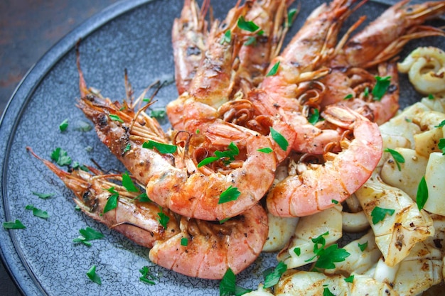 Photo plate with seafood, king prawns and squid, fish menu in the restaurant, dark background