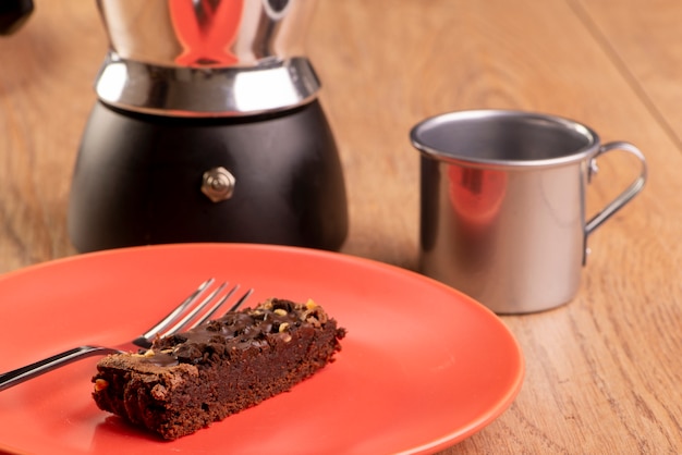 Photo plate with a slice of brownie, a coffee maker and a cup of coffee.