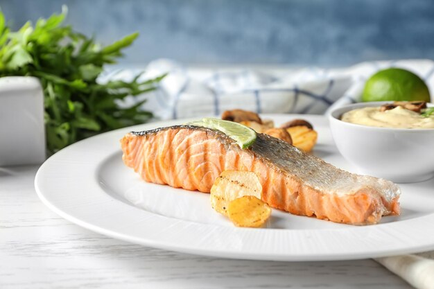 Plate with slice of delicious salmon and fish sauce on table