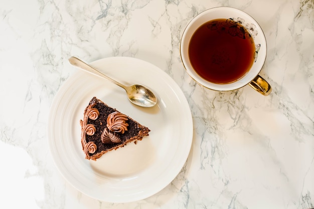 写真 大理石の背景に自家製チョコレートケーキとイエローゴールドのお茶のスライスをプレートします。スペースをコピーします。上面図。クリスマス年末年始の朝食のコンセプト