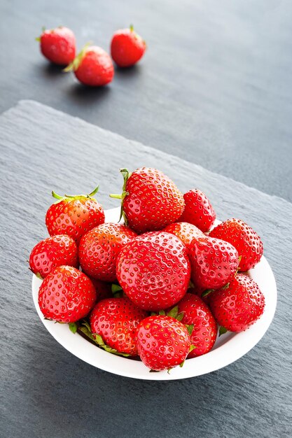 Plate with strawberries Strawberries in a white plate on a gray background Healthy berries