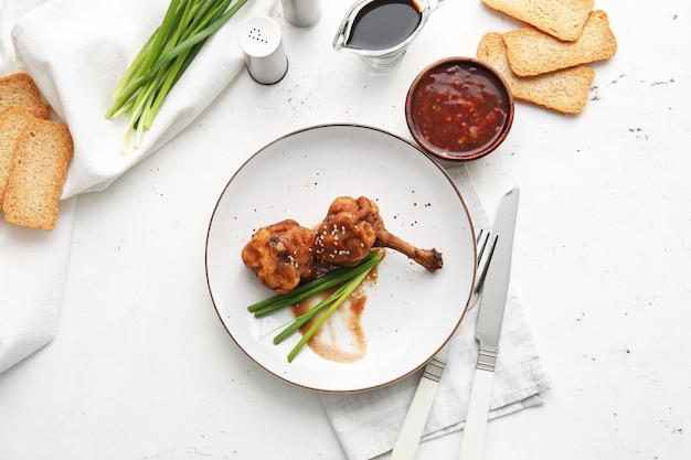 Plate with tasty chicken lollipops on light surface