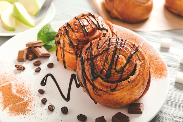 Plate with tasty cinnamon buns on table