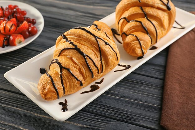 Plate with tasty croissants on wooden table