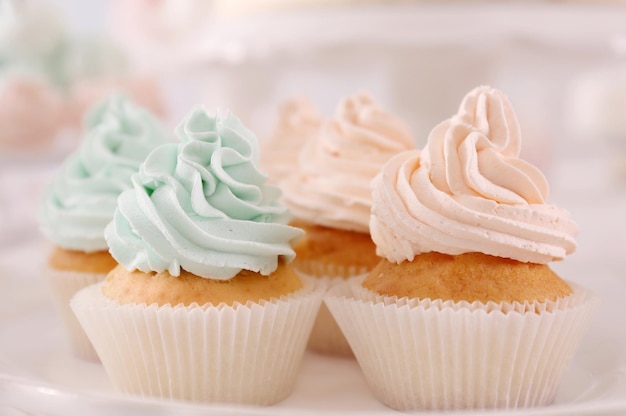 Plate with tasty cupcakes on table closeup