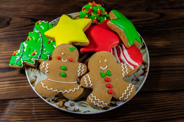 크리스마스 트리 모양의 맛있는 크리스마스 진저브레드 쿠키가 있는 접시, 진저브레드 맨, 별, 그리고 나무 테이블에 크리스마스 스타킹