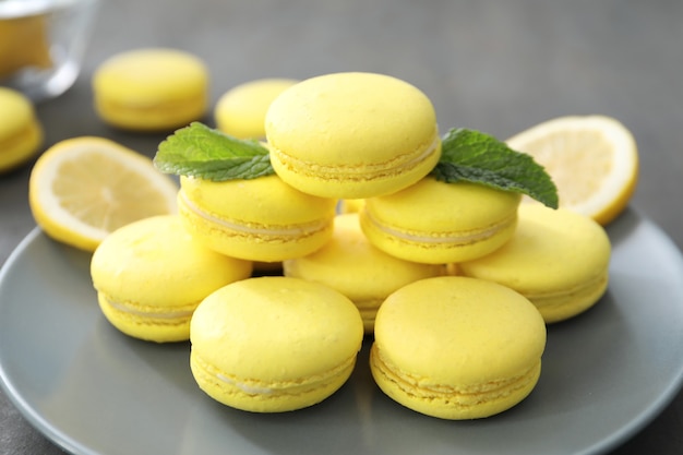 Plate with tasty homemade lemon macarons on table