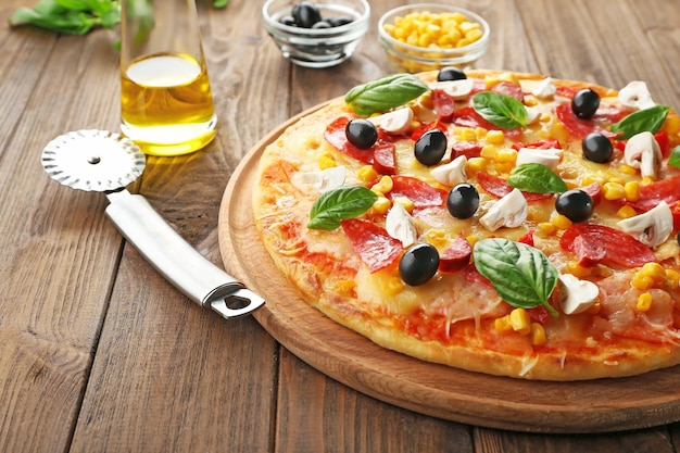 Plate with tasty pizza its ingredients and knife on wooden table