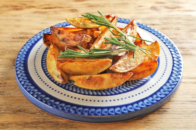 Photo plate with tasty potato wedges on table