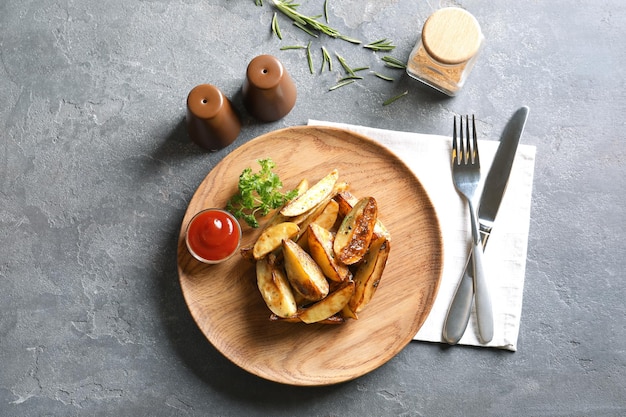 Plate with tasty potato wedges and tomato sauce on table