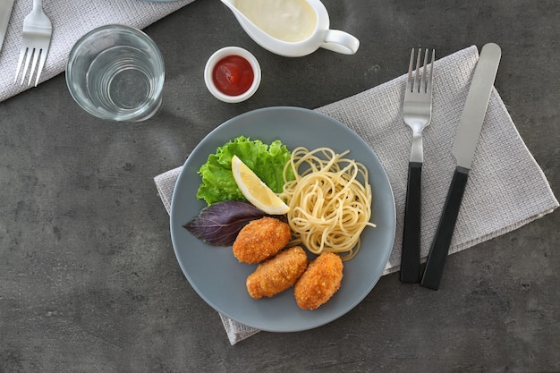 Plate with tasty salmon croquettes and spaghetti on table