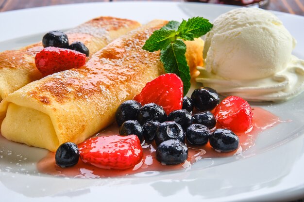 Plate with thin pancakes stuffed with curd and served with berry jam